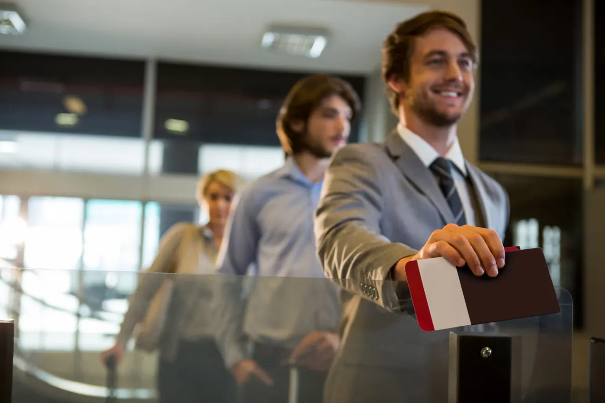 Viajero sonriente con pasaporte y boarding pass en el aeropuerto